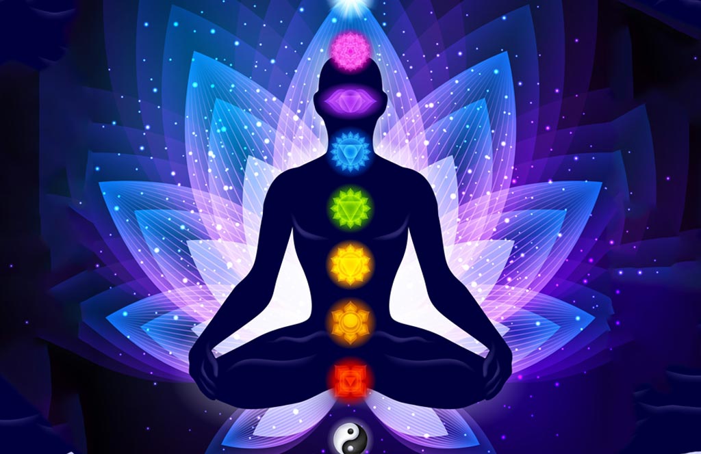 A person meditating with hands resting down on their knees, with seven chakras aligned in the center of the body against a background of radiant, colorful lotus petals, depicting the awakening of energy.